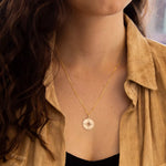 9ct Yellow Gold Compass Pendant from Harrogate Jewellers, a bespoke piece perfect for gifting, featured on a blurred urban background.