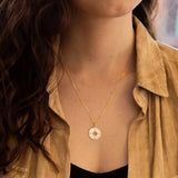 9ct Yellow Gold Compass Pendant from Harrogate Jewellers, a bespoke piece perfect for gifting, featured on a blurred urban background.