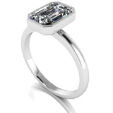 Vivienne Engagement Ring by Harrogate Jewellers, featuring a lab-grown emerald cut diamond, bezel set on a platinum band, displayed on a white backdrop.