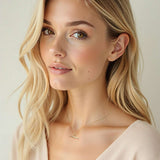 Close-up of a Diamond T-Bar Necklace in 18ct Yellow Gold from Harrogate Jewellers, featuring baguette cut and round brilliant Earth Mined Diamonds on a woman's neck