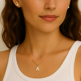 Close-up of a woman wearing a gold necklace with a 'A' pendant.